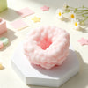 A pink squishy sensory stress ball fidget toy resting on a white surface with small star-shaped confetti nearby.