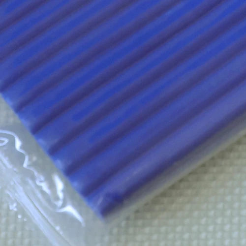A close-up view of a blue polymer clay kit with ribbed texture resting on a light surface.