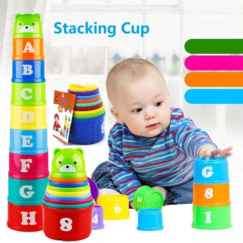 A baby is playing with a colorful stacking cup game featuring letters and numbers like A, B, C, D, E, F, G, H, and 1 through 