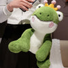 A plush toy of a green frog prince with a yellow crown being held by a person.
