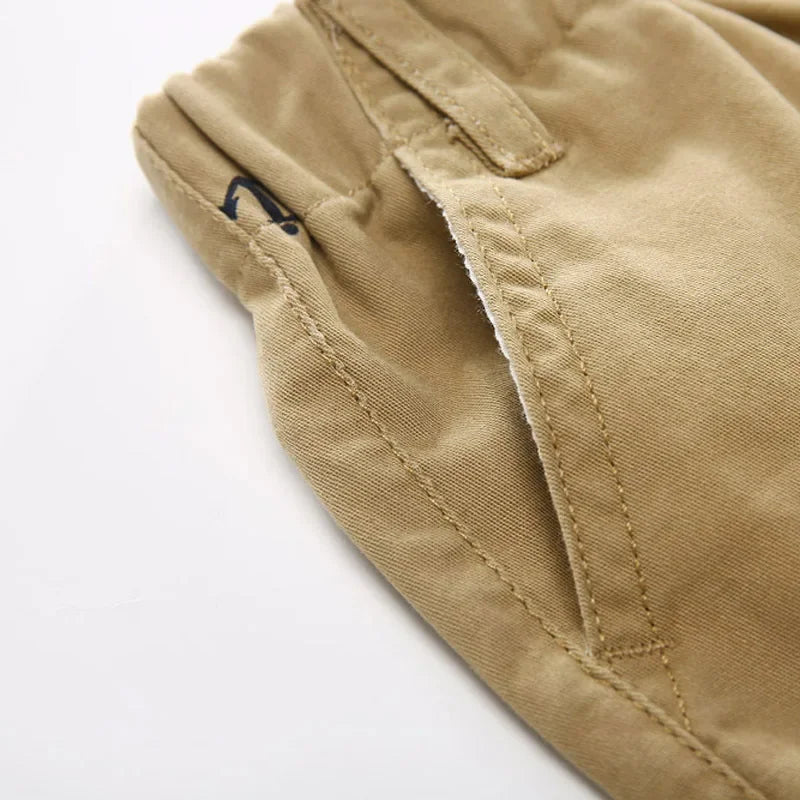 Tan cotton beach shorts featuring a small navy anchor print detail.