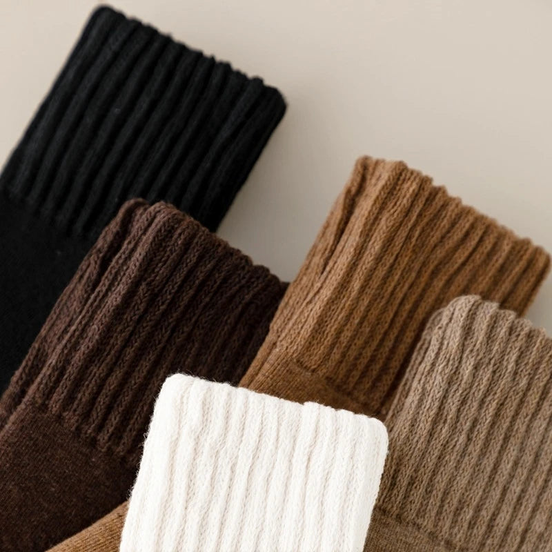 A stack of women's fleece-lined slouch socks in various earthy tones including black, brown, beige, and cream.
