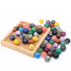 A collection of polished crystal spheres in various shades of purple, pink, green, and yellow arranged on a wooden tray.