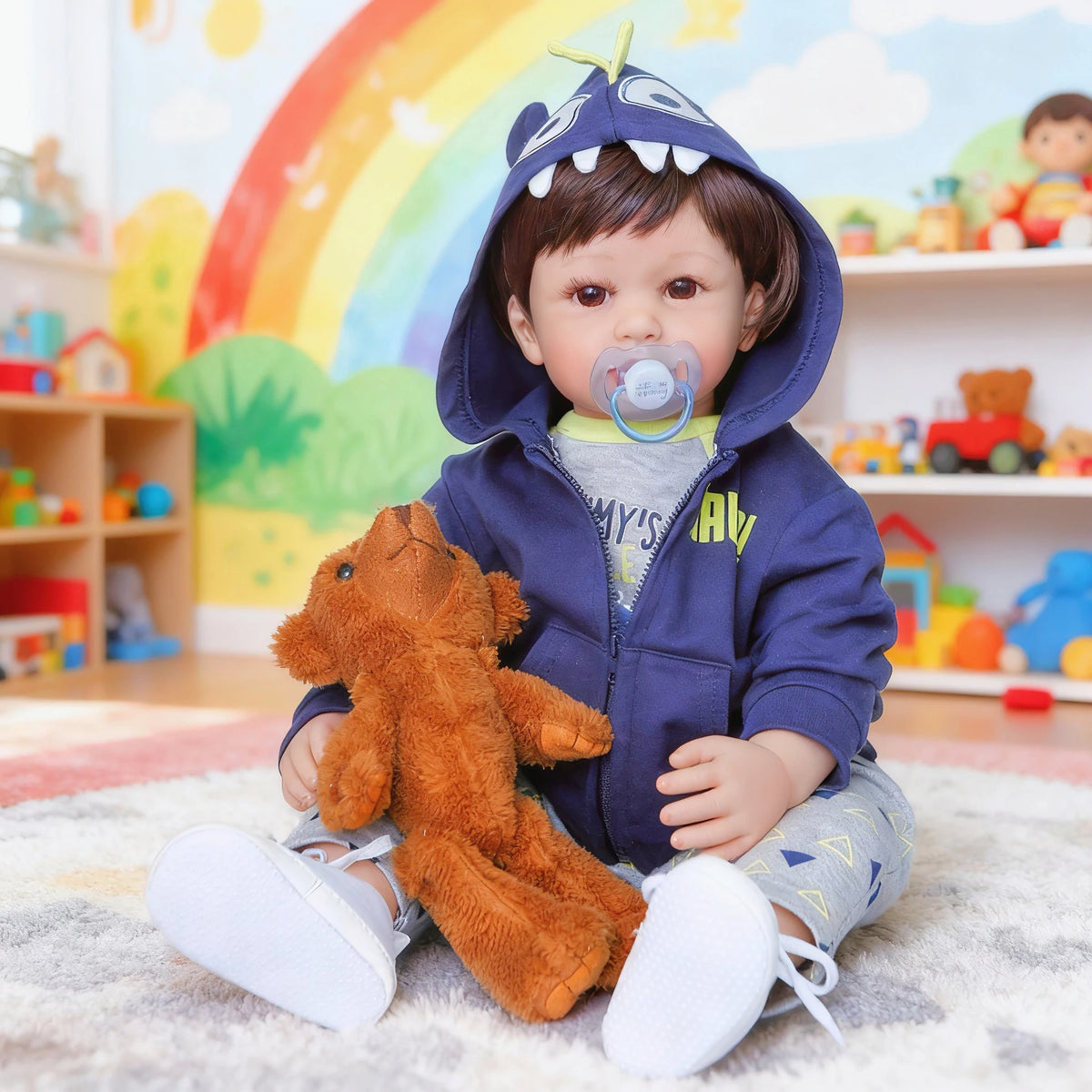 A baby wearing a blue hoodie sitting on a rug with an orange stuffed animal.
