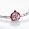 A red fruit charm bead set featuring a polished, round bead encrusted with various colored gemstones on a sterling silver bra