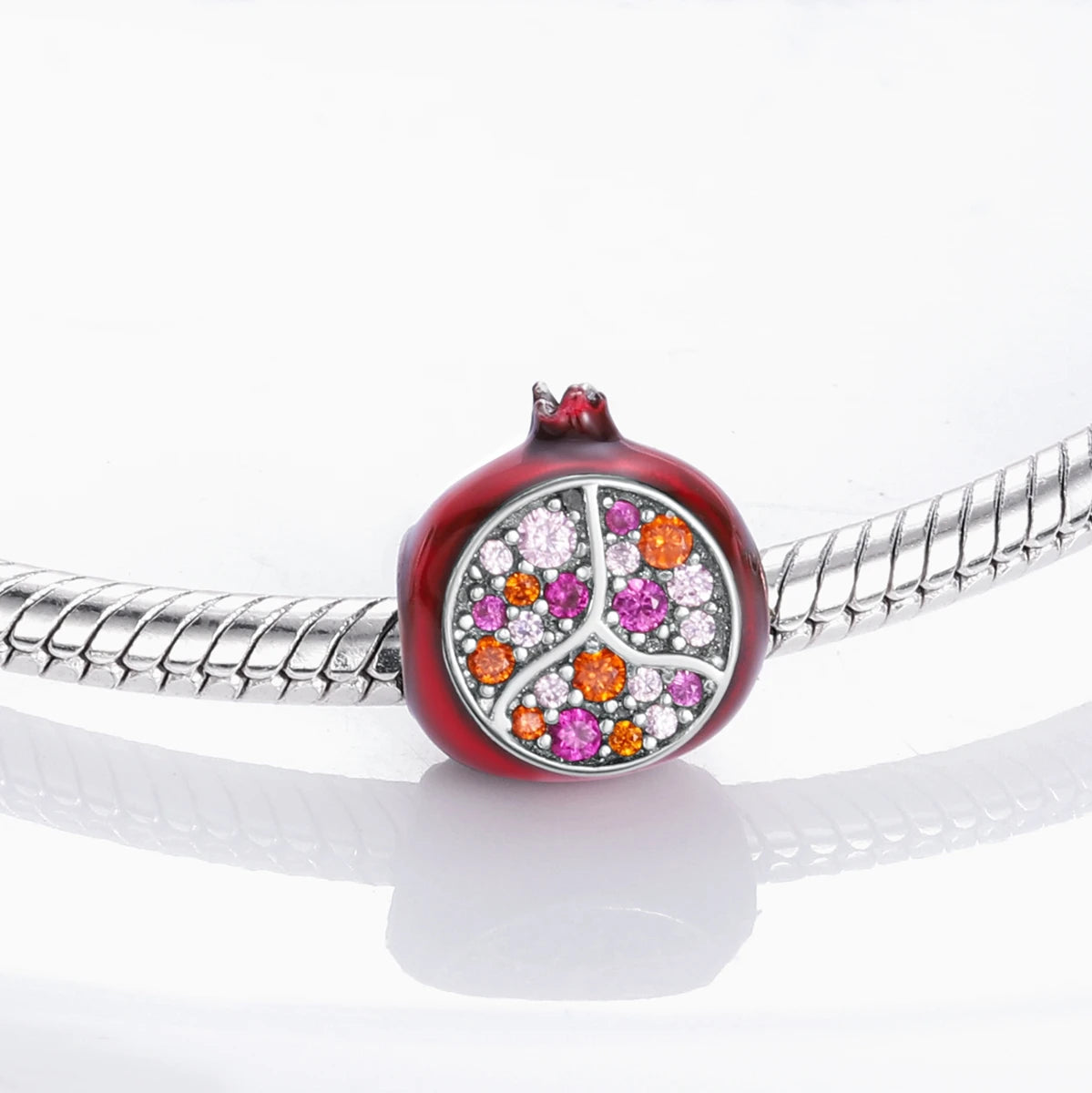 A red fruit charm bead set featuring a polished, round bead encrusted with various colored gemstones on a sterling silver bra