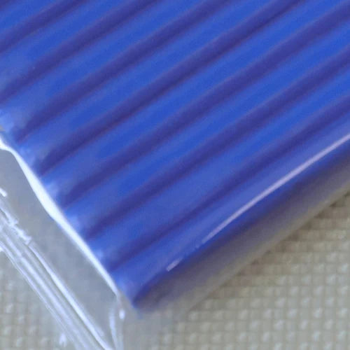 A close-up view of a rectangular block of smooth, blue polymer clay modeling material.