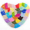 A heart-shaped arrangement of colorful silicone lentil beads in various shades of pink, red, yellow, green, blue, and purple.