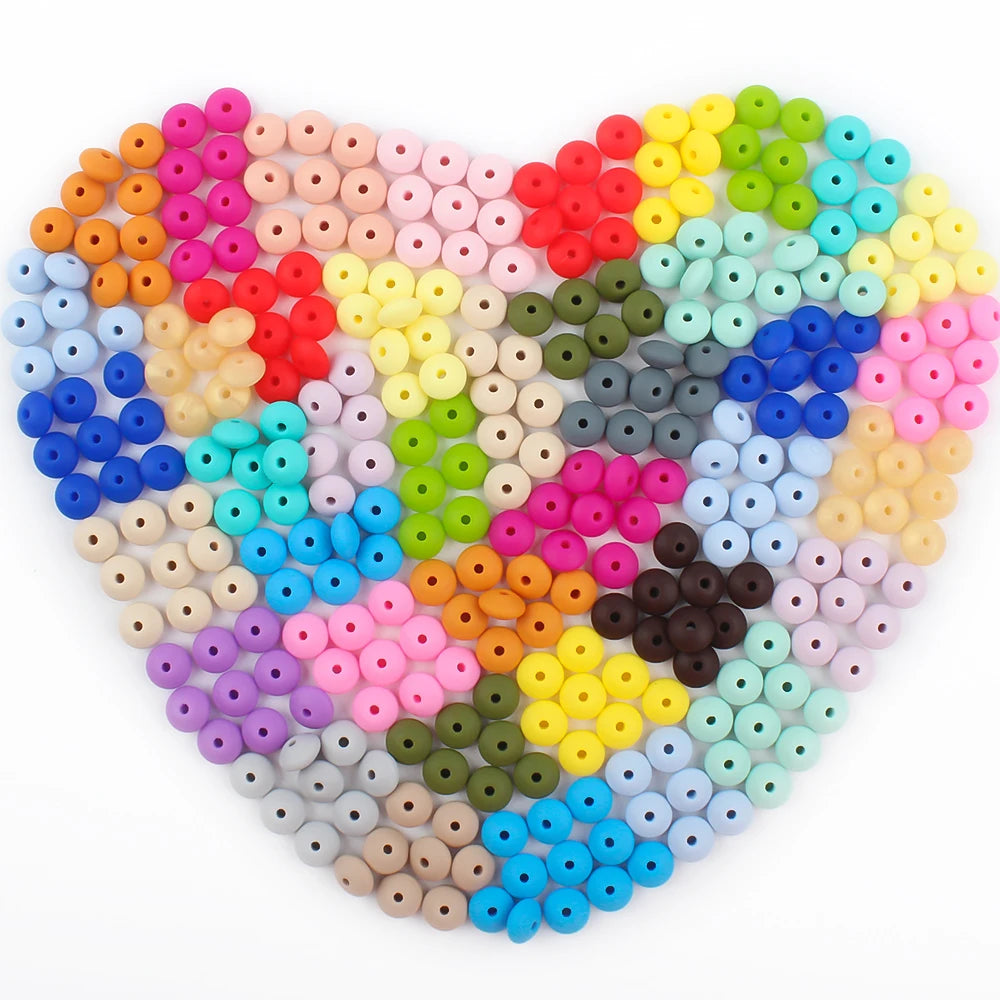 A heart-shaped arrangement of colorful silicone lentil beads in various shades of pink, red, yellow, green, blue, and purple.