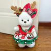 A white plush teddy bear wearing a festive red and green dress with reindeer antlers and a snowflake decoration.
