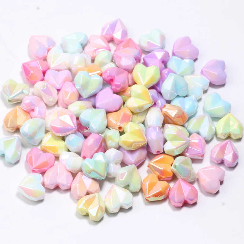 A pile of small, iridescent heart-shaped acrylic beads in various pastel colors like pink, purple, and mint green.