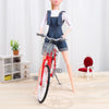 A mini doll wearing a denim overalls set and white t-shirt standing next to a red bicycle.