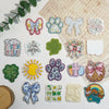 A collection of 10 glitter acrylic flatback resin cabochons featuring various shapes like paw prints, flowers, and bows.