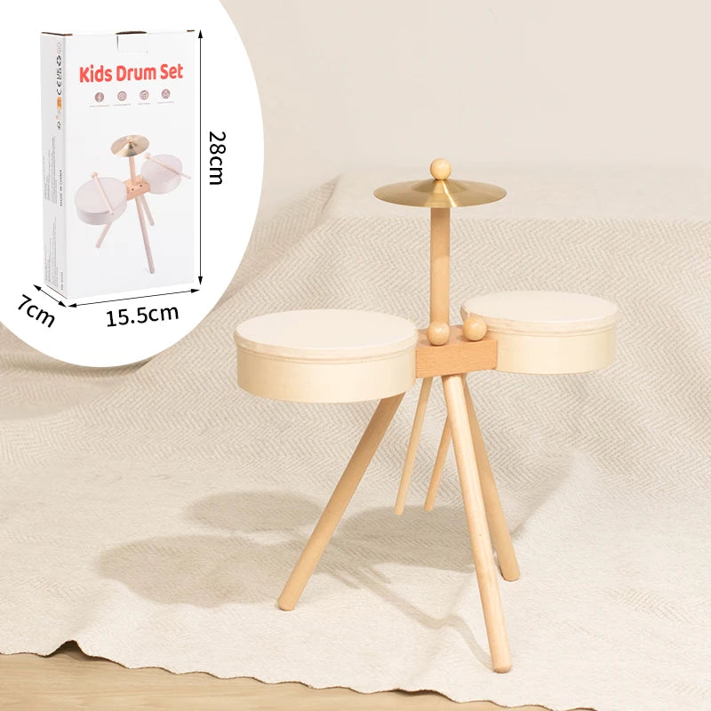 A wooden kids drum set with two drums and mallets displayed on a light beige fabric.