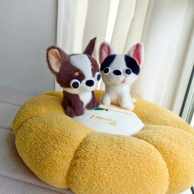 A small white and brown Chihuahua plush doll with its tongue out sitting on a yellow textured surface.