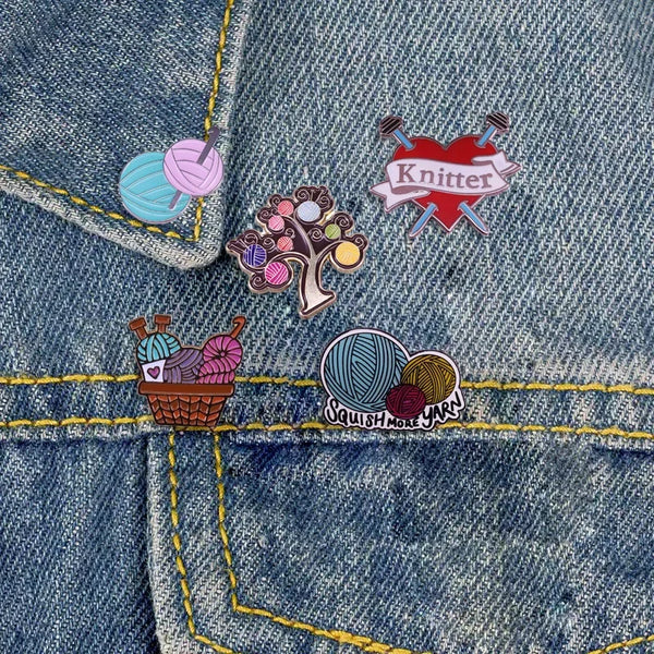 A denim fabric featuring enamel pins and a stitched yellow thread detail.