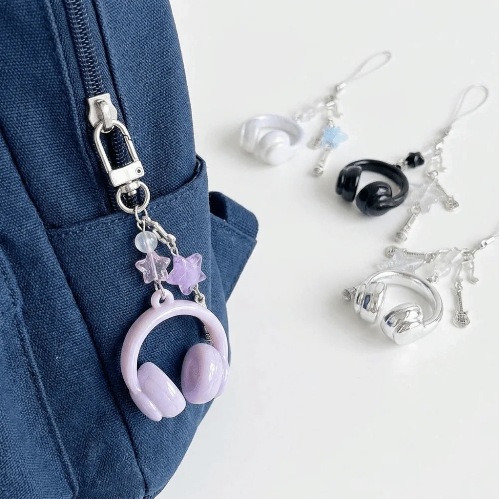A collection of beaded wing cross phone lanyards and keychains hanging from a dark blue fabric.