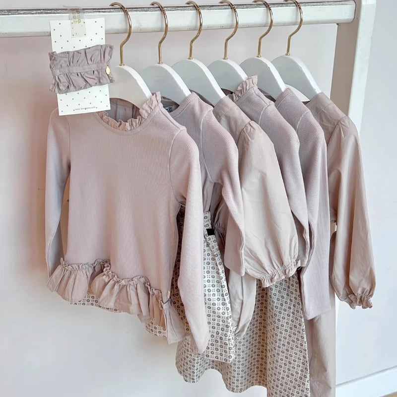 A set of light pink knit sweater and pants for a toddler, displayed on a white rack.