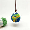 A handcrafted crochet globe charm with a blue and green design hanging from a brown leather cord.