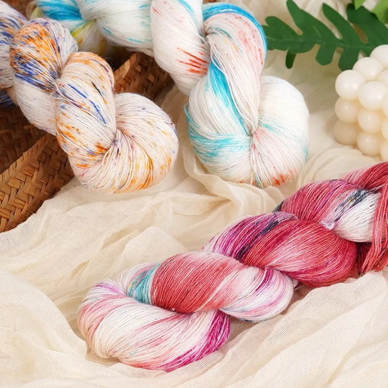 Hand-dyed Australian wool yarn in gradient colors, including pink, blue, and white, shown in skeins.