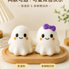 Two white squishy ghost stress balls with purple bows resting on a wooden tray