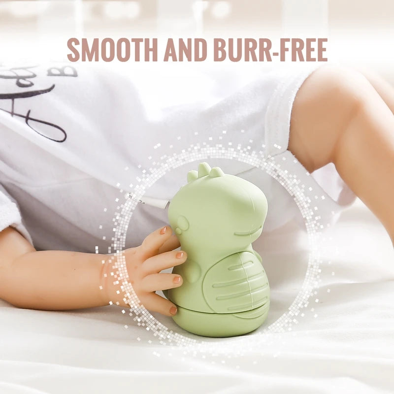 A light green silicone animal bath toy is shown being held by a baby on white fabric.