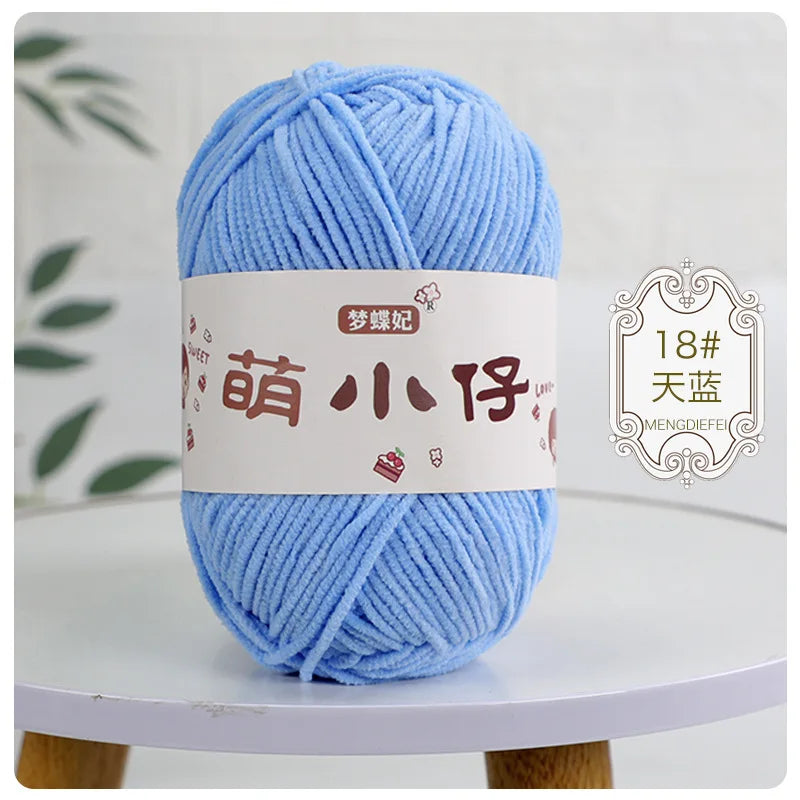 A ball of light blue chenille yarn with a white label featuring Chinese characters for knitting and crochet.