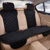 A black car seat protector with a quilted pattern is shown installed in the back seat of a vehicle.