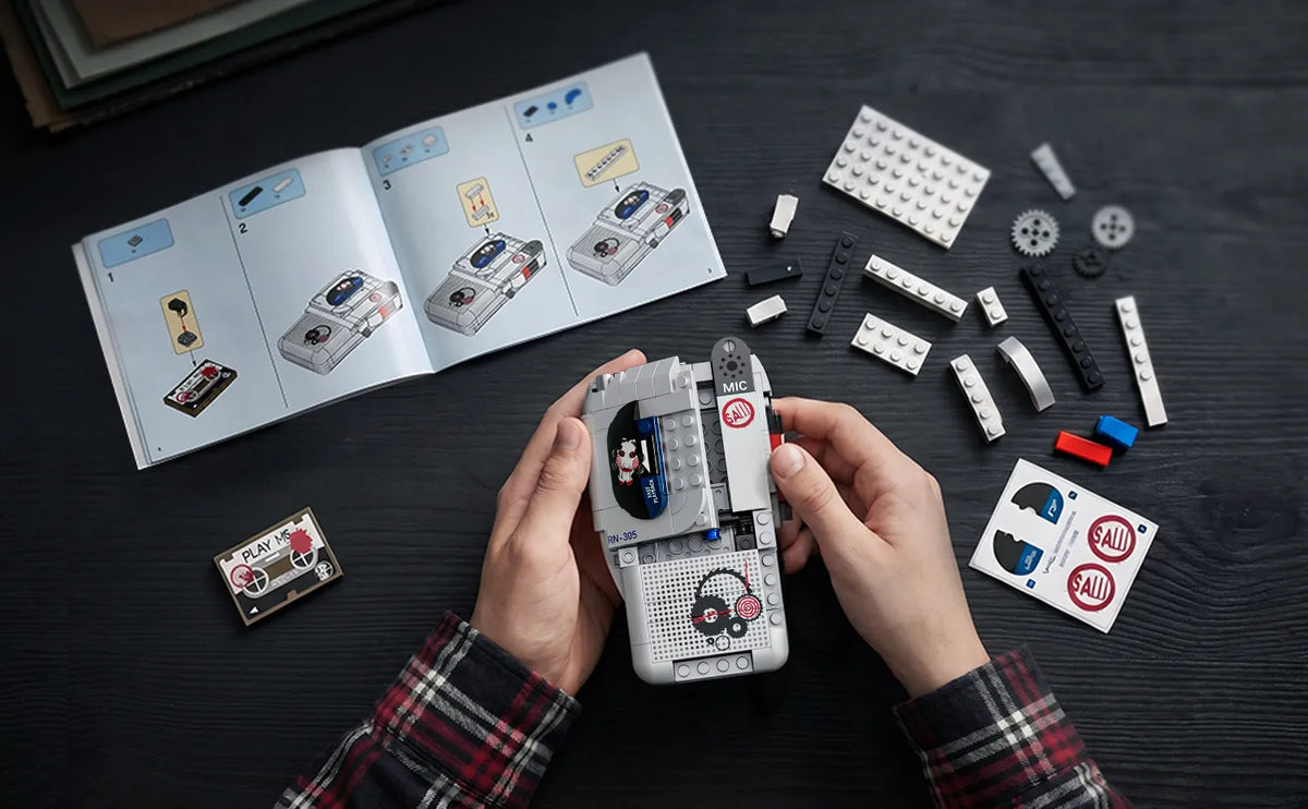 Hands hold a JAKI Horror Movie Puppet Model Building Set with Voice Recorder next to an open instruction manual.