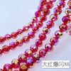 A close-up of a strand of bright red and pink Austrian crystal beads with an AB coating.