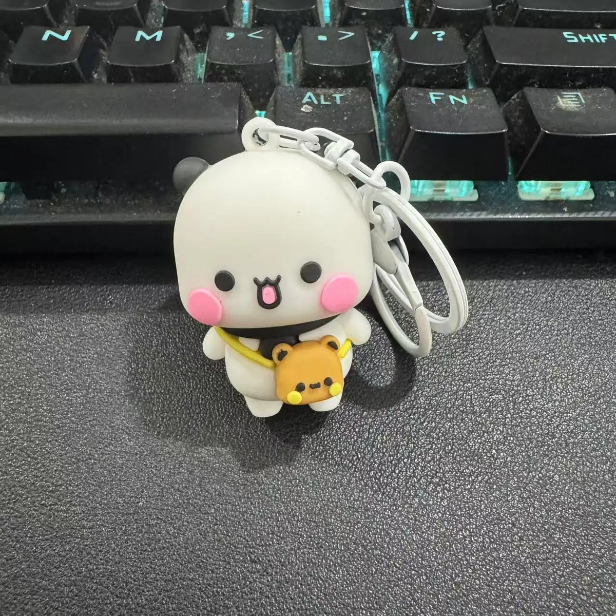 A white cartoon bear couple keychain set with pink accents and a yellow bear charm resting on a black keyboard.