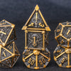 A set of seven metal dice featuring a skull and dragon design in gold and dark metal tones.