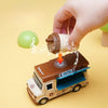 A hand is placing a small coffee cup into the open door of a brown 1:36 scale dining car toy truck.