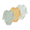 A set of three long-sleeved cotton baby bodysuits in light green, yellow, and white patterned fabric.