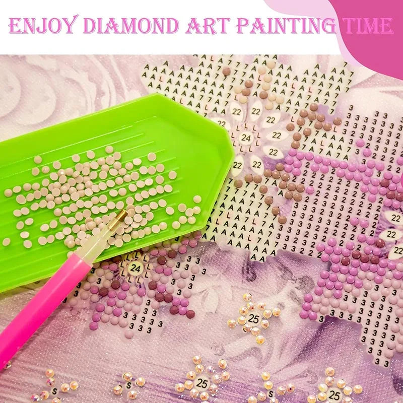 A diamond painting kit showing various colored seed beads and a pink drill pen on a green tray.