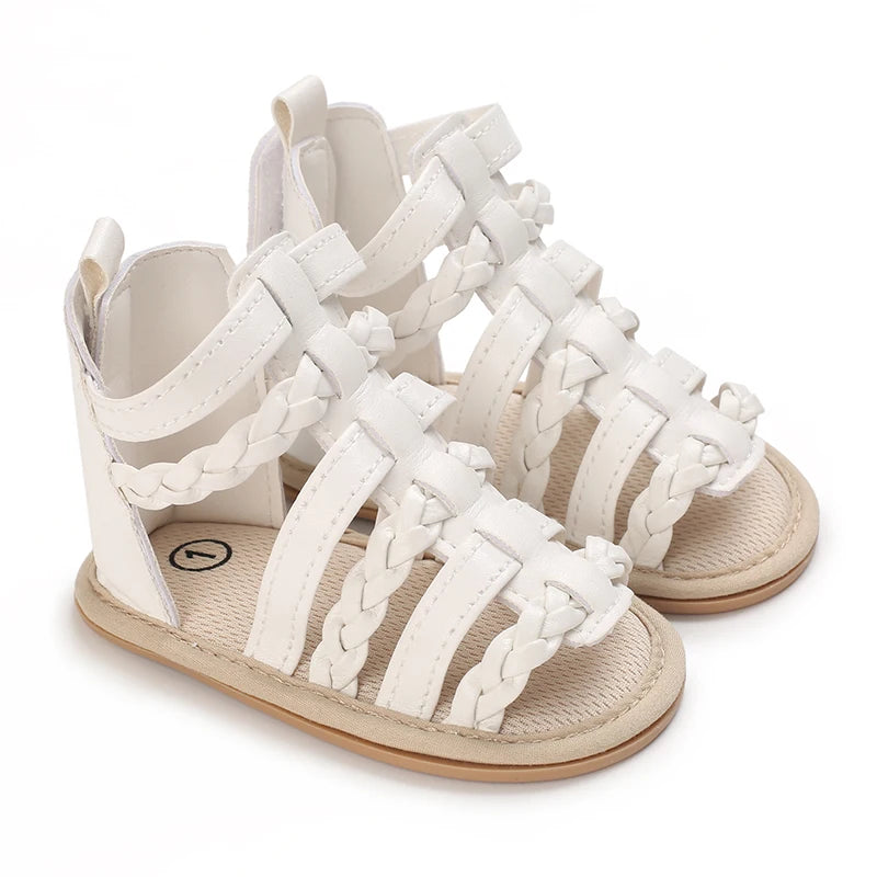 A pair of cream-colored baby first walker sandals with braided straps and a soft anti-slip sole.