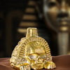 A handcrafted golden Aztec death skull whistle resting on a brown surface.