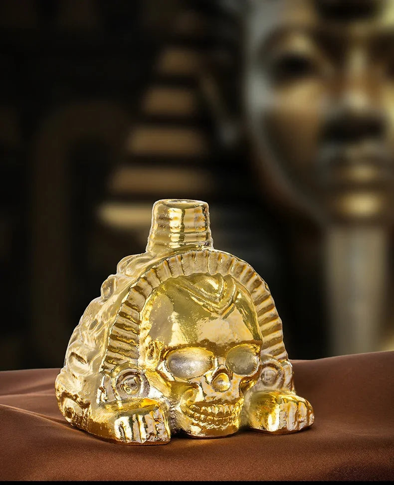 A handcrafted golden Aztec death skull whistle resting on a brown surface.