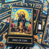 A tarot card depicting the King of Cups with a crown, holding a cup, and surrounded by celestial elements.