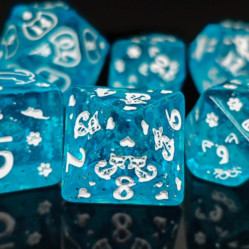 A close-up of bright blue polyhedral dice with white numbering and gold accents, reflecting on a dark surface.