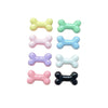 A collection of six small resin bone charms in various pastel and dark colors for nail art and jewelry making