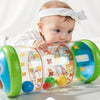 A baby is interacting with a clear plastic crawling roller toy filled with colorful balls and flowers.