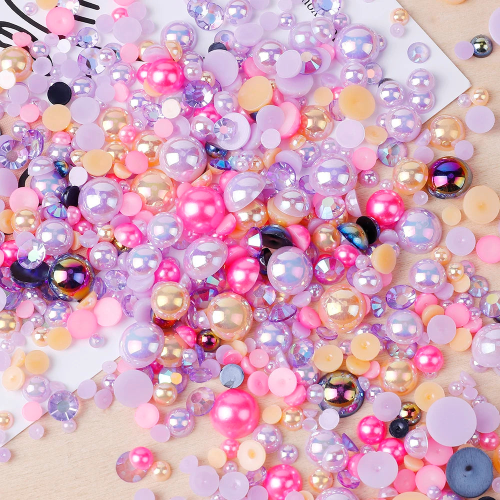 A colorful mix of iridescent resin and rhinestone pearls in pink, purple, and gold shades for crafts and nail art.