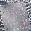 A sheet of nail art stickers featuring various iridescent and pastel winged designs on a light gray background.