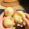 A hand holds several smooth, yellow squishy stress relief clay fidget toys on a metal tray.