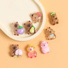 A collection of small resin figurines depicting capybaras and other cute animals in various colors on a light background.