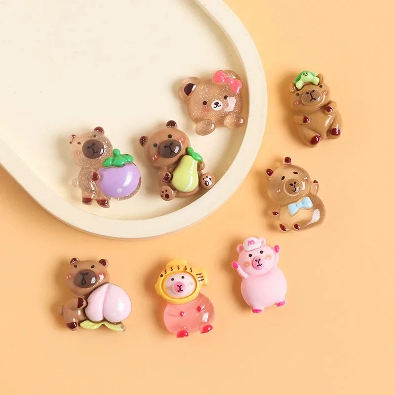 A collection of small resin figurines depicting capybaras and other cute animals in various colors on a light background.