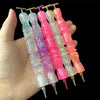 A hand holds a set of glitter resin diamond painting pens with colorful, wavy handles.