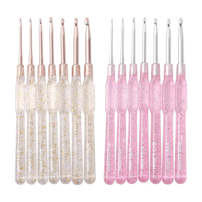 A set of seven aluminum crochet hooks with color-coded pink and clear handles.