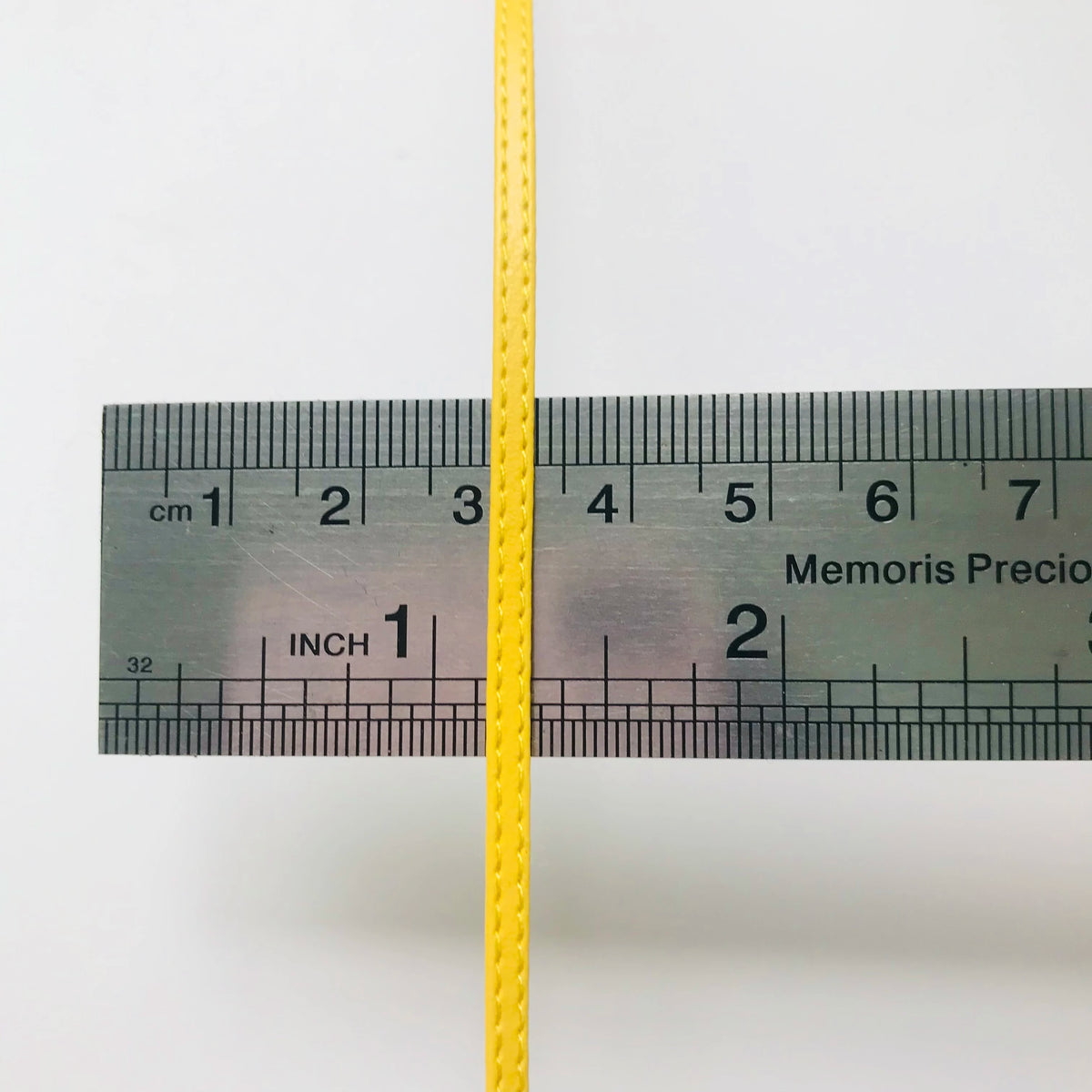 Gelbes Maßband mit Zentimeter- und Zollmarkierungen, das ein dunkles Rechteck überkreuzt.